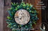 A wreath made of green leaves and flowers, with a white horse image inside the wreath.
