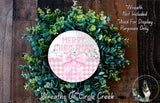 A wreath made of green leaves and a pink bow, with the text "Merry Christmas" displayed on it.
