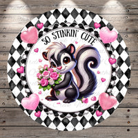 A black and white checkered frame surrounds a cartoon image of a skunk holding a bouquet of pink roses. Surrounding the skunk are pink hearts, and the text "So stinking' cute" is written above the skunk.