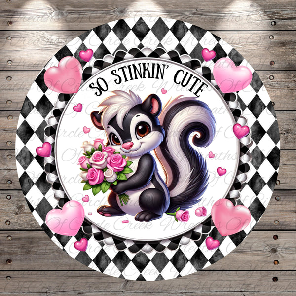 A black and white checkered frame surrounds a cartoon image of a skunk holding a bouquet of pink roses. Surrounding the skunk are pink hearts, and the text "So stinking' cute" is written above the skunk.
