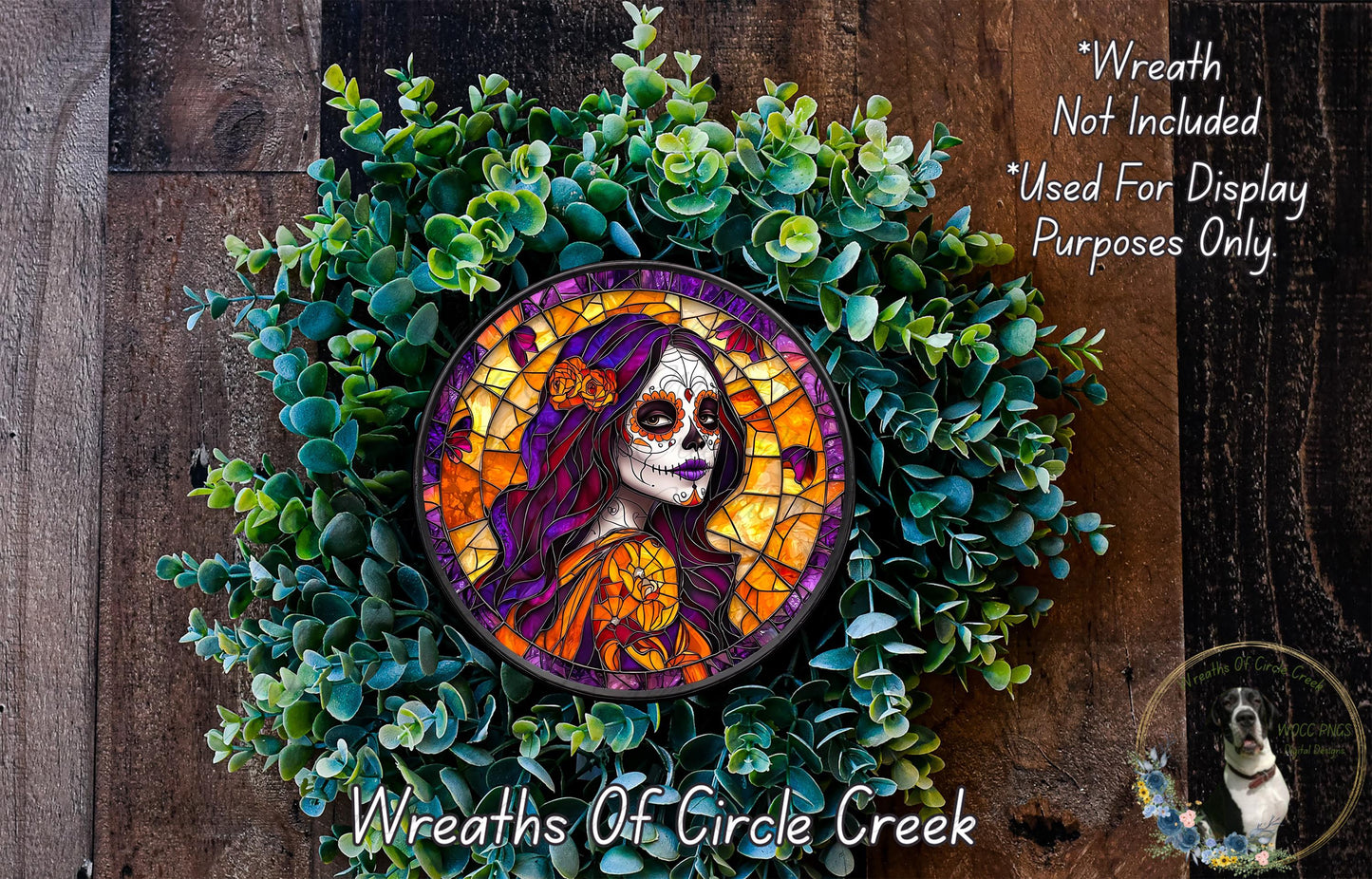 a wreath with a colorful design, including a woman's face with a skull-like appearance, surrounded by green foliage.