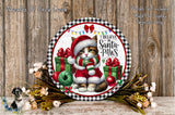A festive wreath featuring a cat dressed in a Santa hat and scarf, surrounded by Christmas decorations such as gift boxes and ornaments. The wreath is set against a wooden background, and there are flowers and greenery surrounding it.