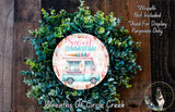 a wreath made of green leaves and a circular design with a colorful ice cream truck on it.