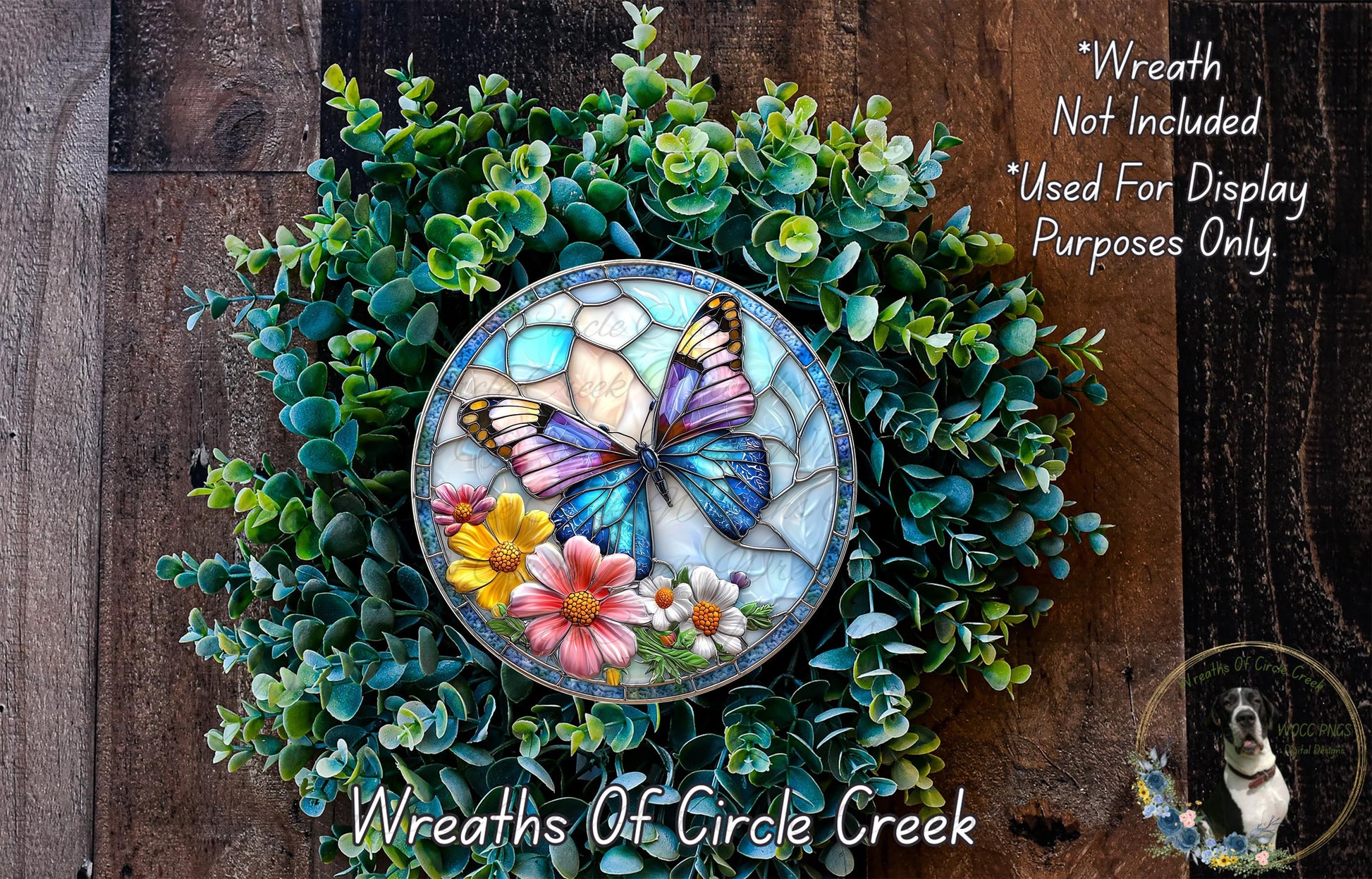 a wreath with a butterfly design, surrounded by various green plants and flowers. The wreath is placed on a wooden surface, and there is a small dog in the background.