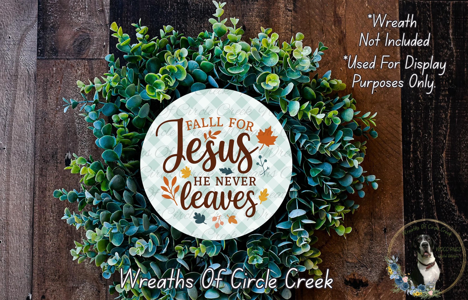 a wreath made of green leaves and a circular sign with the text "Fall for Jesus he never leaves" against a wooden background.