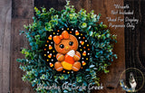 A wreath made of green foliage and featuring a gingerbread man figure holding a candy cane.