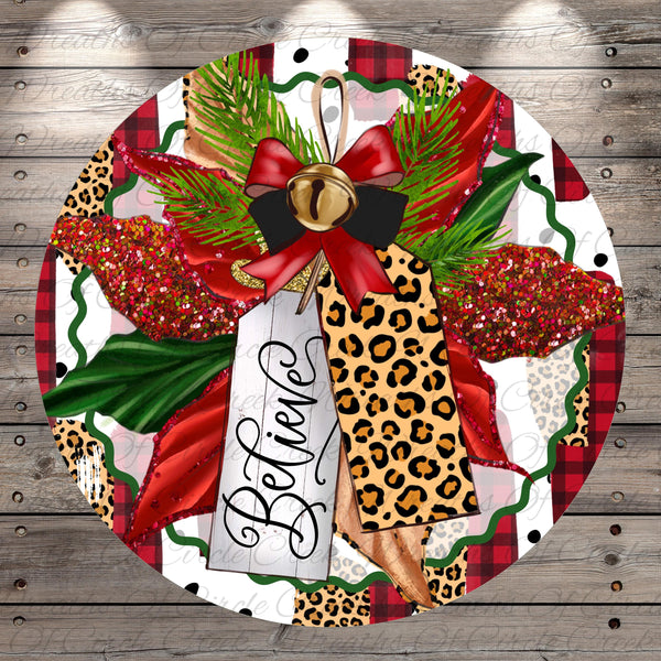 A decorative wreath with a leopard print ribbon, red and gold accents, and a tag that says "Believe". The wreath is set against a wooden background with a plaid pattern.