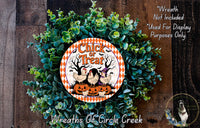 a wreath made of green foliage and a decorative orange and white sign that reads "Chick or Treat". The sign is surrounded by a sprig of greenery, creating a festive and seasonal atmosphere.