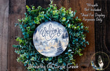 a wreath with a snowy village scene displayed on it, surrounded by a lush green wreath.