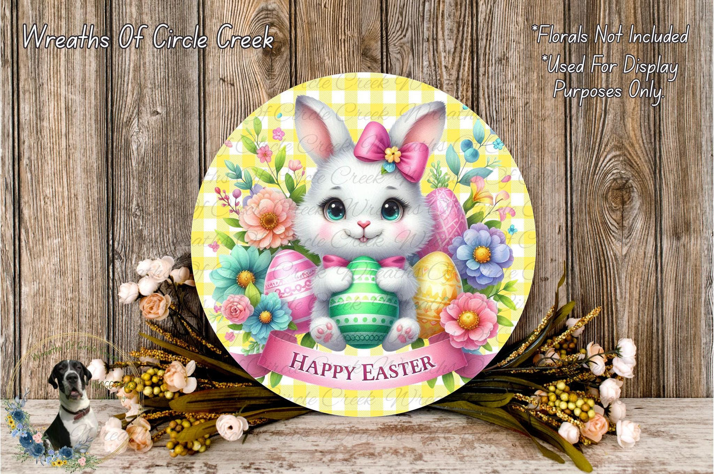 A round wooden plaque with a white bunny holding a green Easter egg, surrounded by colorful flowers and a banner that says "Happy Easter".