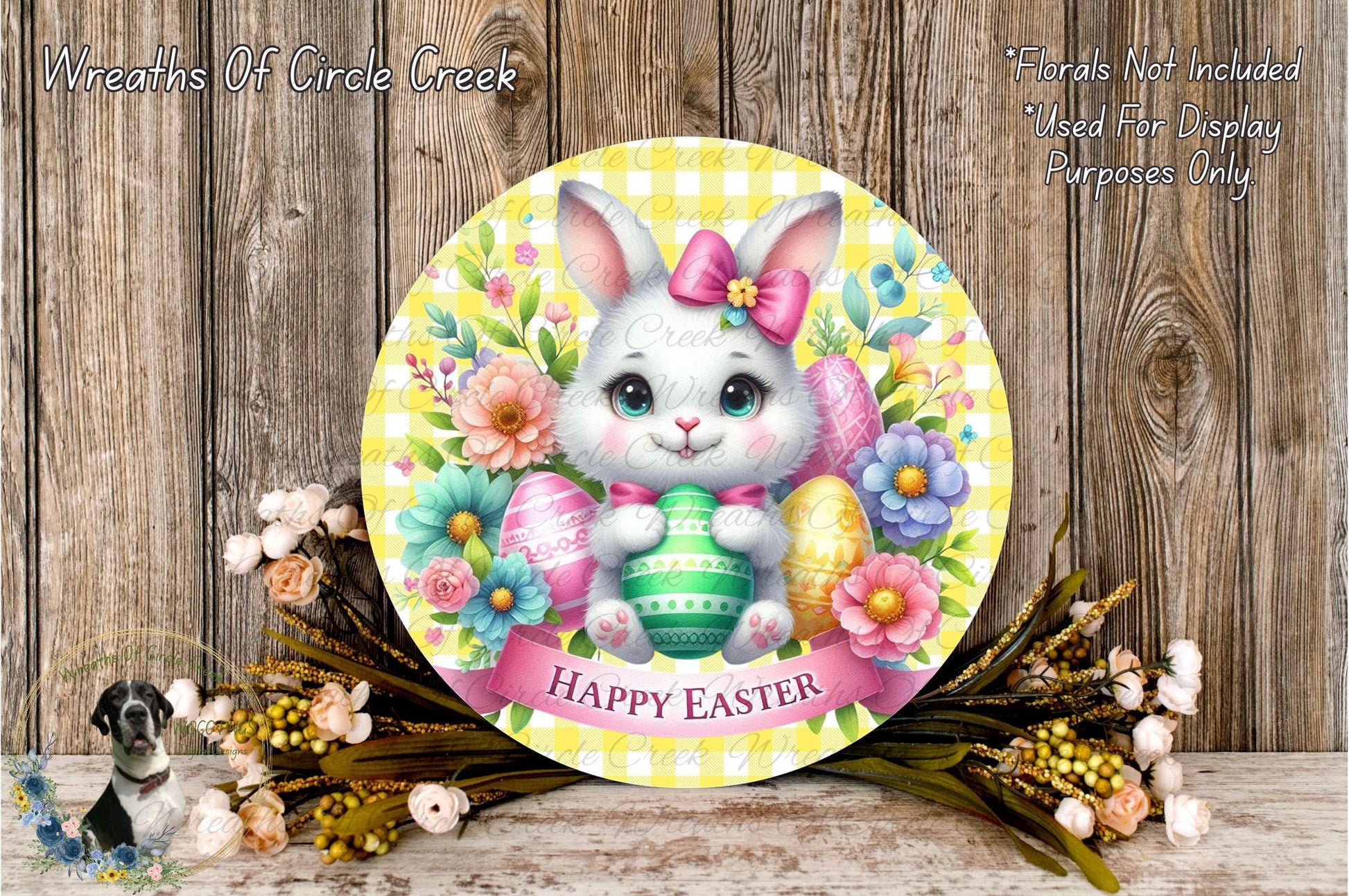 A round wooden plaque with a white bunny holding a green Easter egg, surrounded by colorful flowers and a banner that says "Happy Easter".