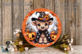 A decorative Halloween wreath featuring a cute bear wearing a witch's hat, surrounded by pumpkins and flowers, with a wooden background.
