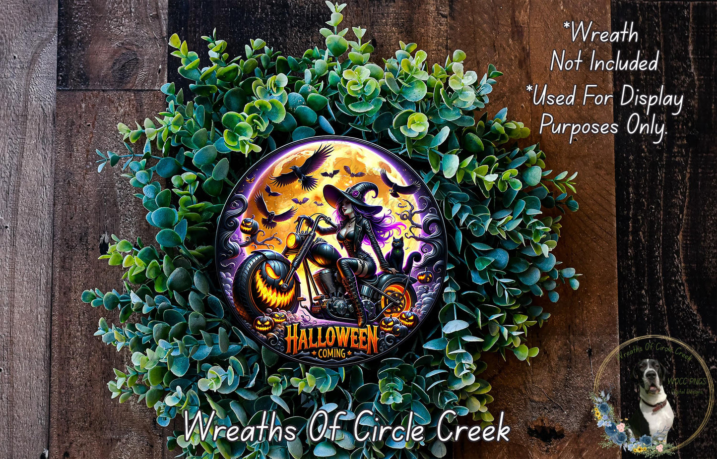 A Halloween-themed wreath made of green foliage and featuring a central image of a witch riding a motorcycle against a full moon backdrop.