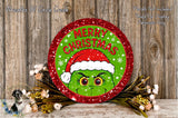 A festive Christmas wreath with a green Grinch wearing a Santa hat, surrounded by flowers and a wooden background.