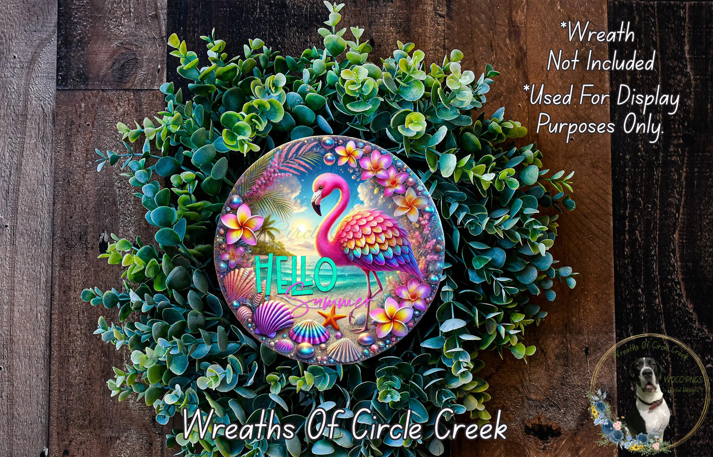 A colorful wreath with a pink flamingo and various flowers, including a "Hello" sign, is displayed on a wooden surface.