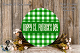 a circular green and white checkered sign with the text "Happy St. Patrick's Day" displayed on it, surrounded by a wreath of flowers and a wooden background.