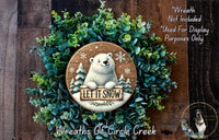 A wreath made of green plants and a wooden sign featuring a polar bear holding a sign that says "Let it snow".