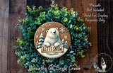 A wreath made of green plants and a wooden sign featuring a polar bear holding a sign that says "Let it snow".