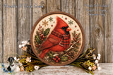 A round wooden plaque featuring a red cardinal bird, surrounded by holiday decorations such as pine cones, berries, and flowers, against a wooden background.