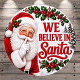 Santa Claus with his hand over his mouth, surrounded by holly, berries, and the text "We believe in Santa".