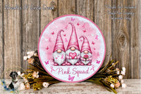 a round sign with three pink gnomes holding pink roses, surrounded by pink flowers and greenery. The sign has the text "Pink Squad" written on it.