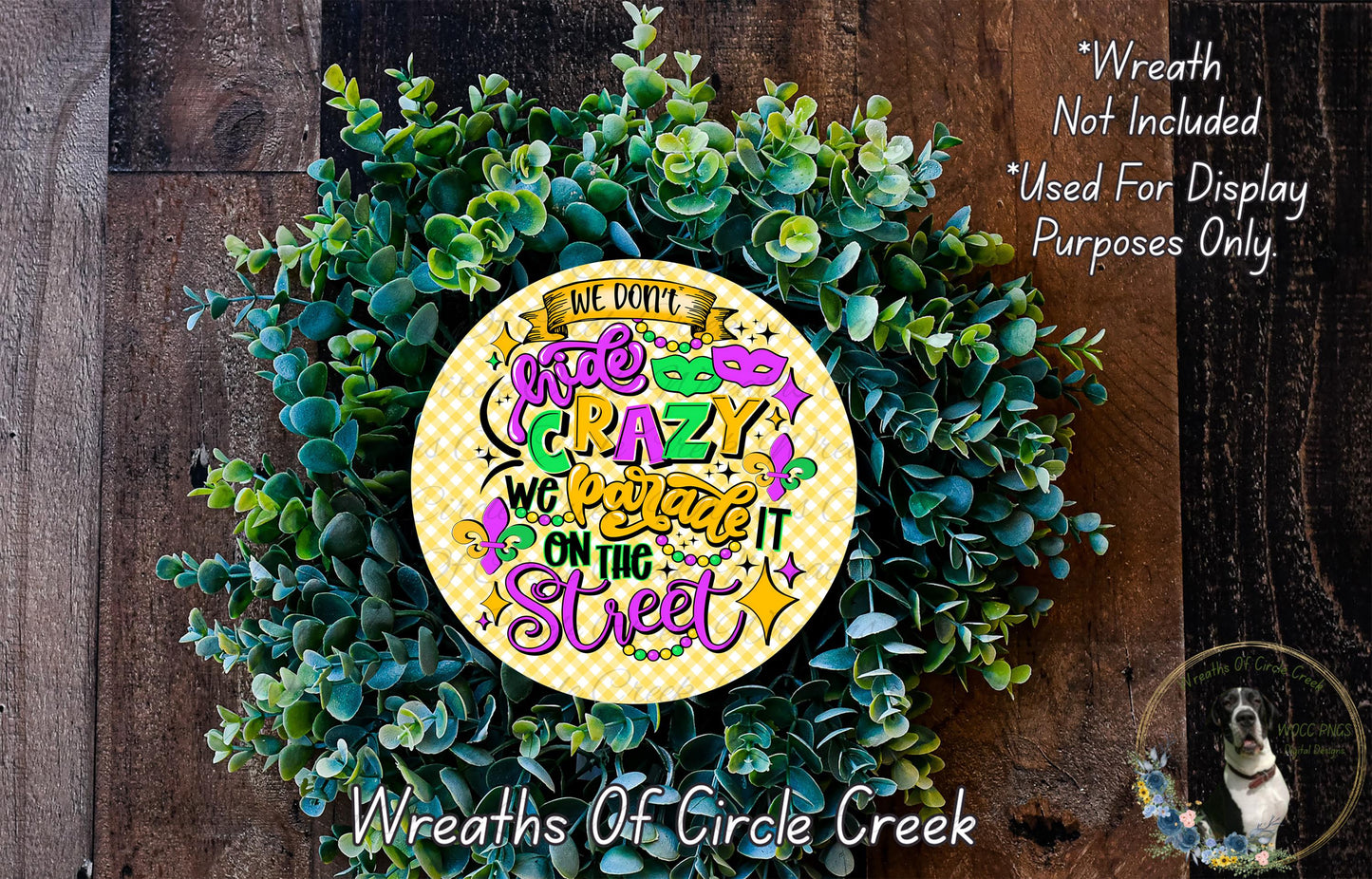 a wreath made of green leaves and a yellow circular sign with text, placed on a wooden surface.