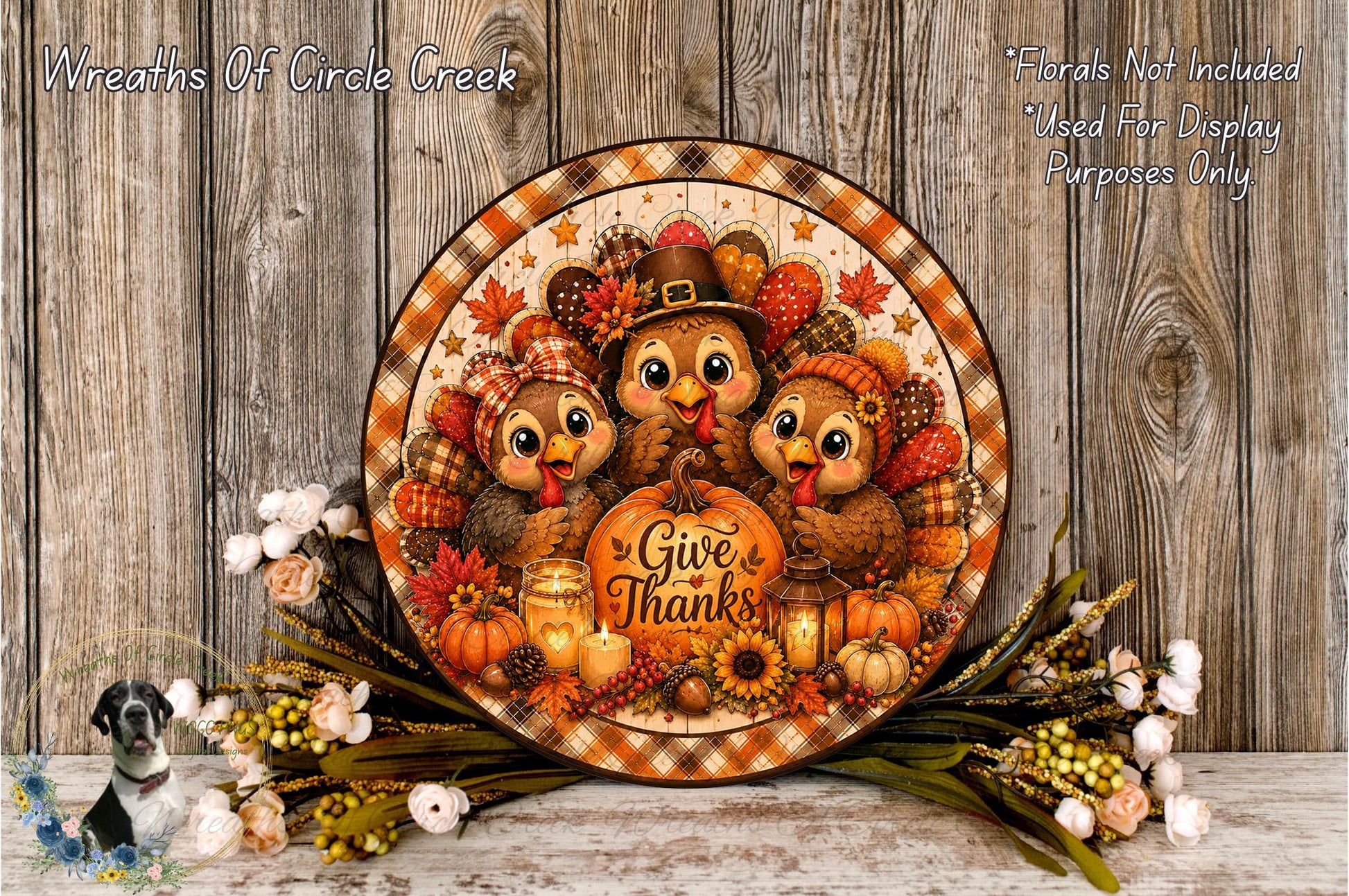 A decorative Thanksgiving wreath with a central design featuring three cartoon turkeys, a pumpkin, and other fall-themed elements. The wreath is surrounded by flowers and placed on a wooden surface.