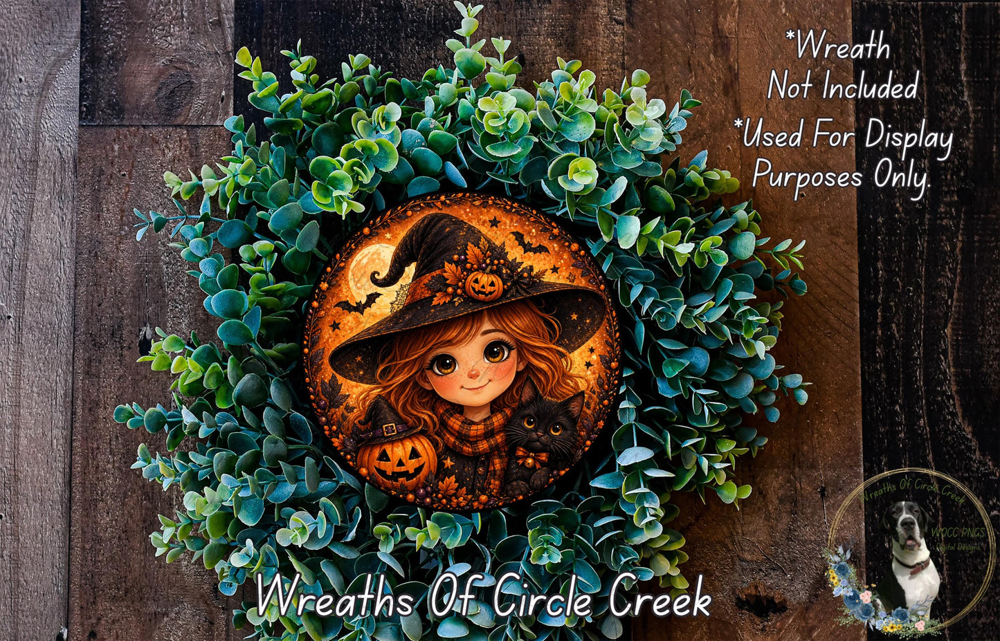 A wreath featuring a cartoon illustration of a young girl wearing a witch's hat, holding a pumpkin and a cat, surrounded by green foliage.
