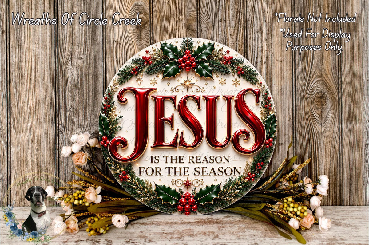 a circular sign with the text "JESUS IS THE REASON FOR THE SEASON" surrounded by a wreath of holly, berries, and other holiday decorations. The sign is placed on a wooden surface, and there are additional floral arrangements in the background.