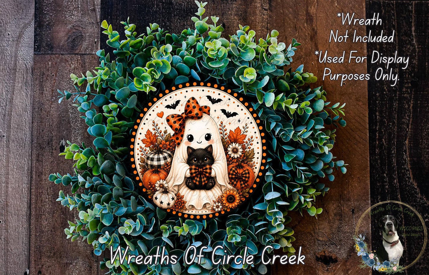 a Halloween-themed wreath with a ghost, cat, and pumpkins, set against a backdrop of green foliage.