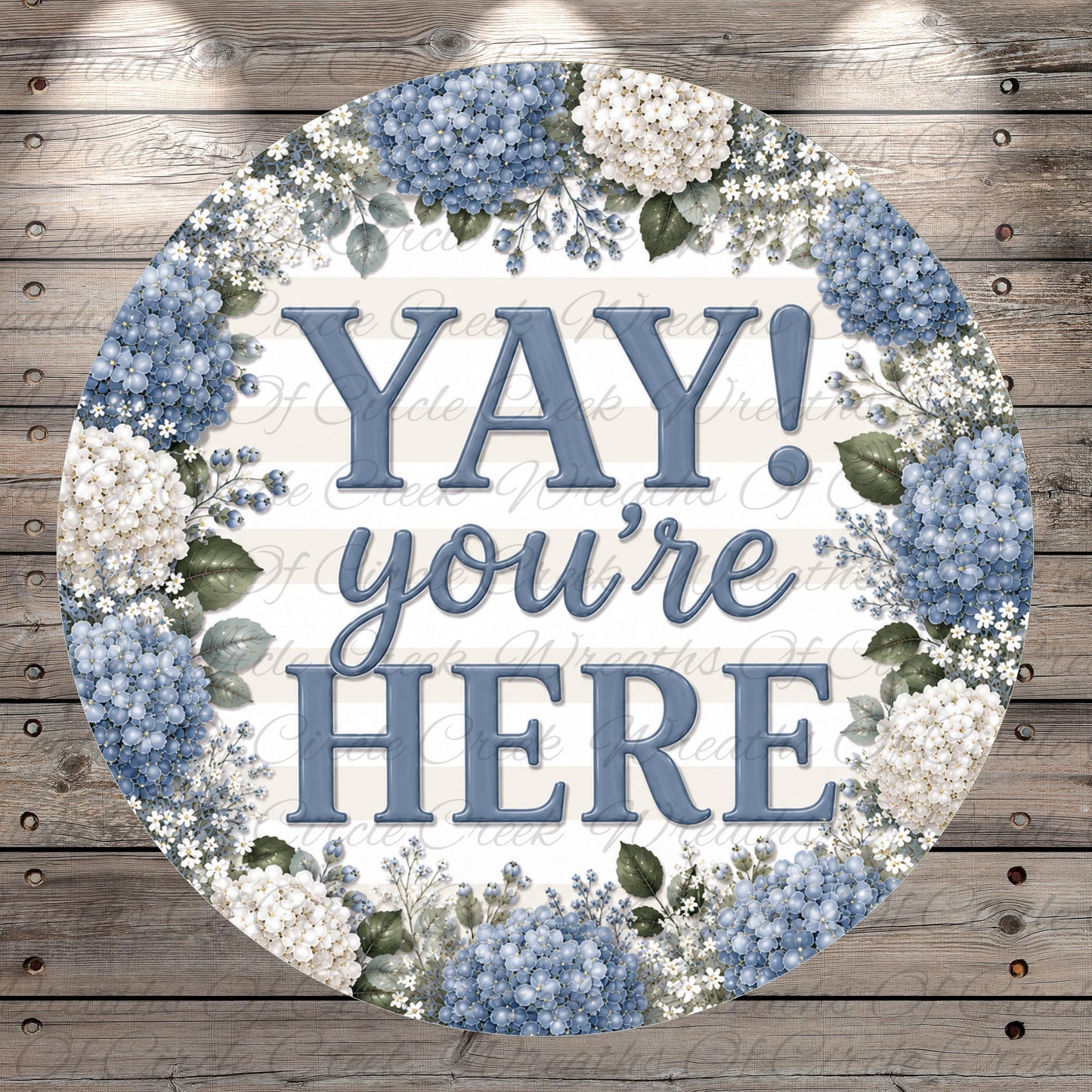 A circular sign with the text "YAY you're here" surrounded by a floral border of blue hydrangeas and white flowers.