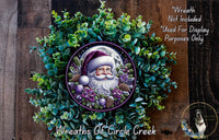 A wreath featuring a Santa Claus figure surrounded by greenery and flowers, with a full moon visible in the background.