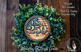 A wreath made of green leaves and a circular emblem with the text "USA 25" and "1776-2026" on it, placed on a wooden surface.