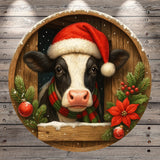 A black and white cow wearing a Santa hat and scarf peeks out from behind a wooden frame adorned with Christmas decorations, including poinsettias and ornaments.