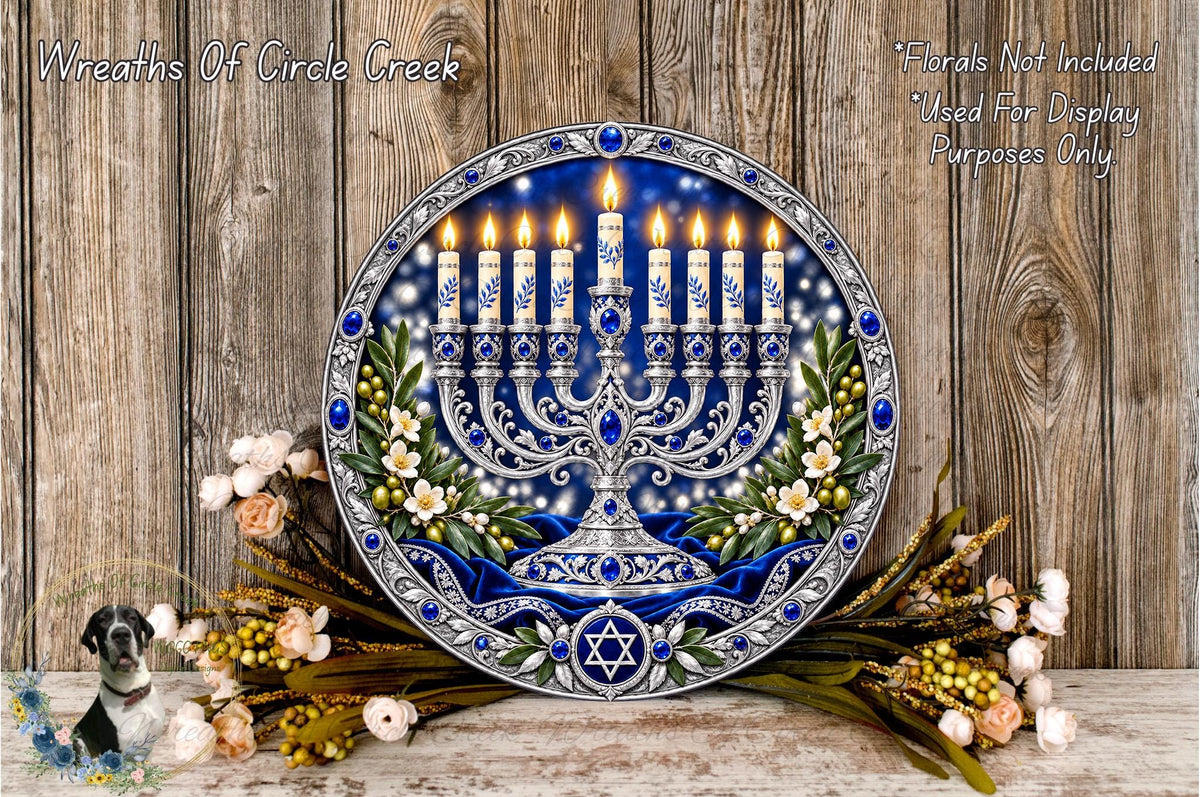 a decorative Hanukkah menorah with lit candles, surrounded by flowers and greenery, placed on a wooden surface.