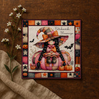 A framed illustration of a young girl dressed as a witch, sitting on a pumpkin and surrounded by Halloween-themed elements such as bats, pumpkins, and flowers.
