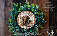 A wreath made of green foliage and featuring a brown dog with a hunting rifle, surrounded by the text "I call the shots" and "Wreaths of Circle Creek".
