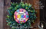 A colorful birthday wreath made of greenery and adorned with candy and cupcakes, featuring the text "Happy Birthday to you" in a vibrant design.