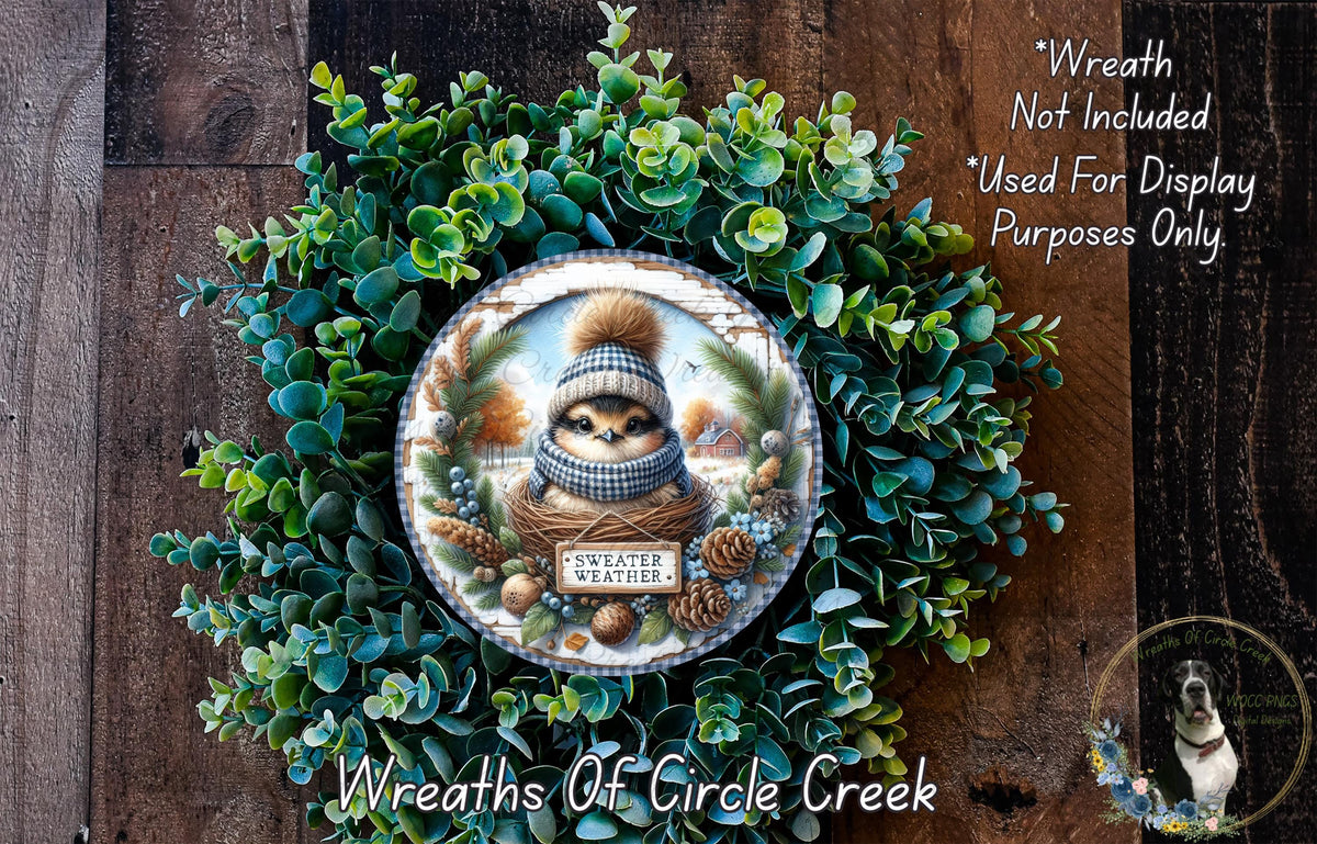 A wreath made of green foliage and pine cones, featuring a small brown squirrel wearing a plaid hat and a "sweater weather" sign.