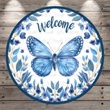 a circular sign with a blue butterfly and blue flowers, surrounded by a wreath of blue flowers and leaves. The sign has the word "Welcome" written on it.