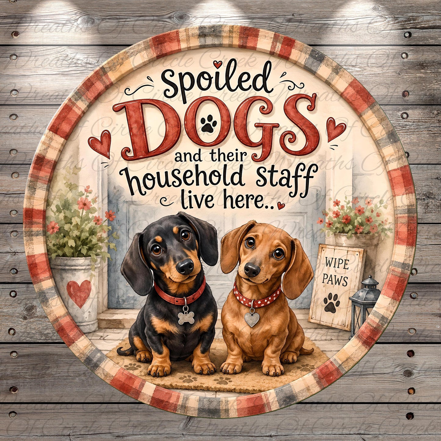 two dogs, one black and one brown, sitting together in front of a house with a sign that says "WIPE PAWS".