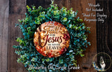 a wreath made of green leaves and a circular ornament with the text "Fall for Jesus he never leaves" displayed on it.