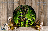 A decorative wreath featuring a green and black striped witch's boot, surrounded by flowers and a wooden background.