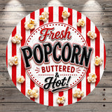 a circular sign with the text "Fresh Popcorn BUTTERED & HOT!" surrounded by popcorn and red and white striped background.