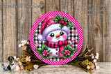 A round, decorative wreath with a snowman figure wearing a red hat and scarf, surrounded by pink and black polka dots, flowers, and a wooden background.