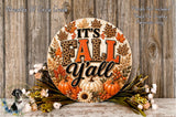 A decorative sign with the text "It's Fall Y'all" surrounded by autumn-themed elements such as leaves, pumpkins, and flowers, placed on a wooden surface.