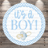 A round blue and white baby announcement sign with the text "It's a BOY!" and a pacifier icon.