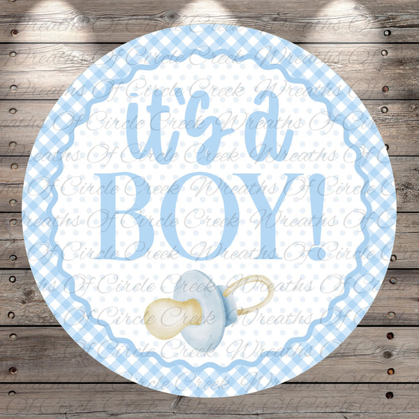 A round blue and white baby announcement sign with the text "It's a BOY!" and a pacifier icon.