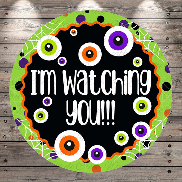 The image is a Halloween-themed sticker with a black background, surrounded by a green border with a pattern of colorful circles and dots. The sticker features the text "I'm watching you!!!" in a playful and festive style.