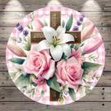 A round floral arrangement with a cross and lilies, set against a pink and white checkered background.